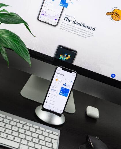 Photo by Balázs Kétyi space gray iPhone X on stand near silver iMac and Apple Magic Keyboard